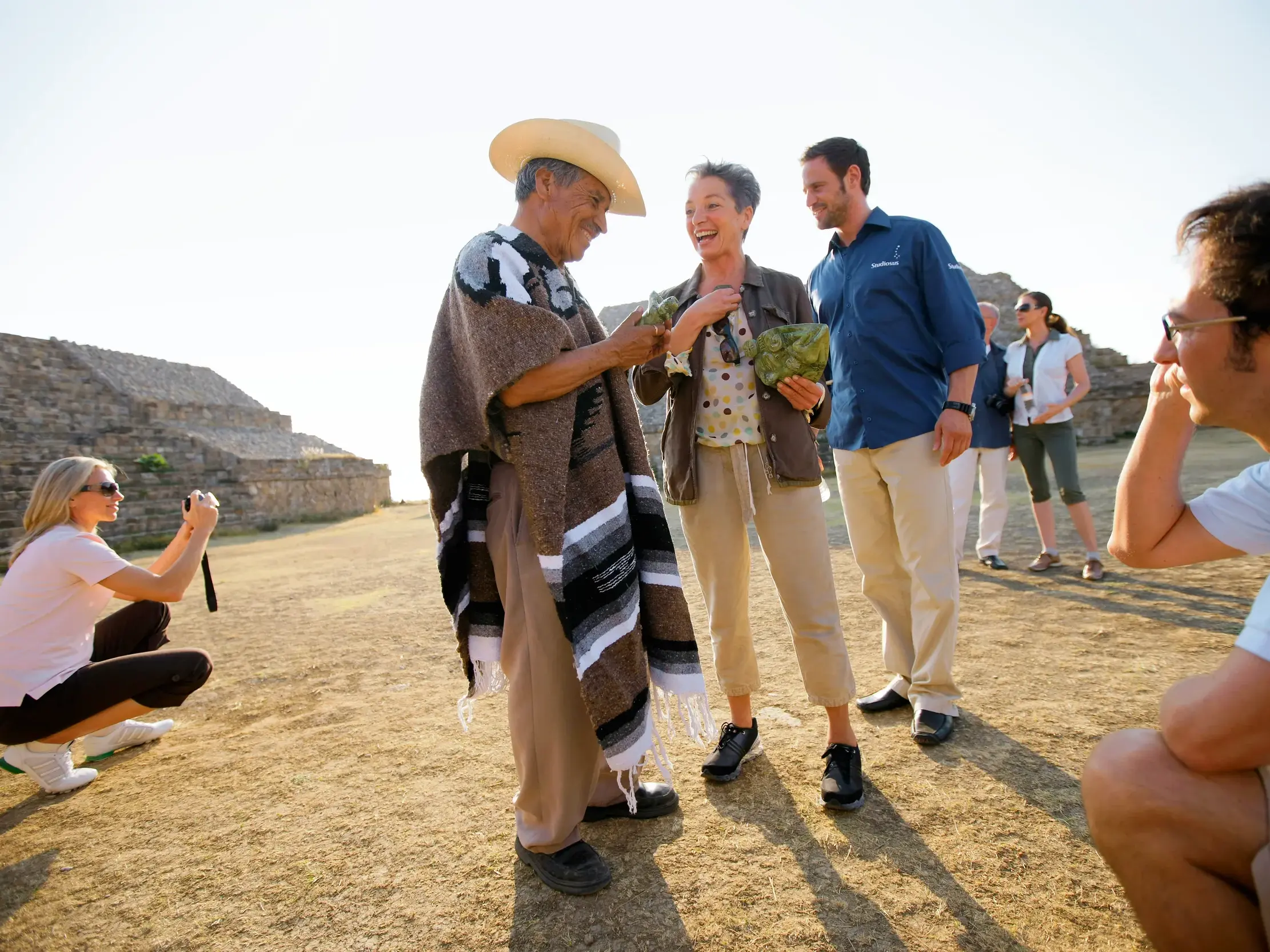Studiosus-Reiseleiter und eine Kleingruppe im Gespräch mit einem Einheimischen in Poncho vor den historischen Ruinen von Teotihuacán.