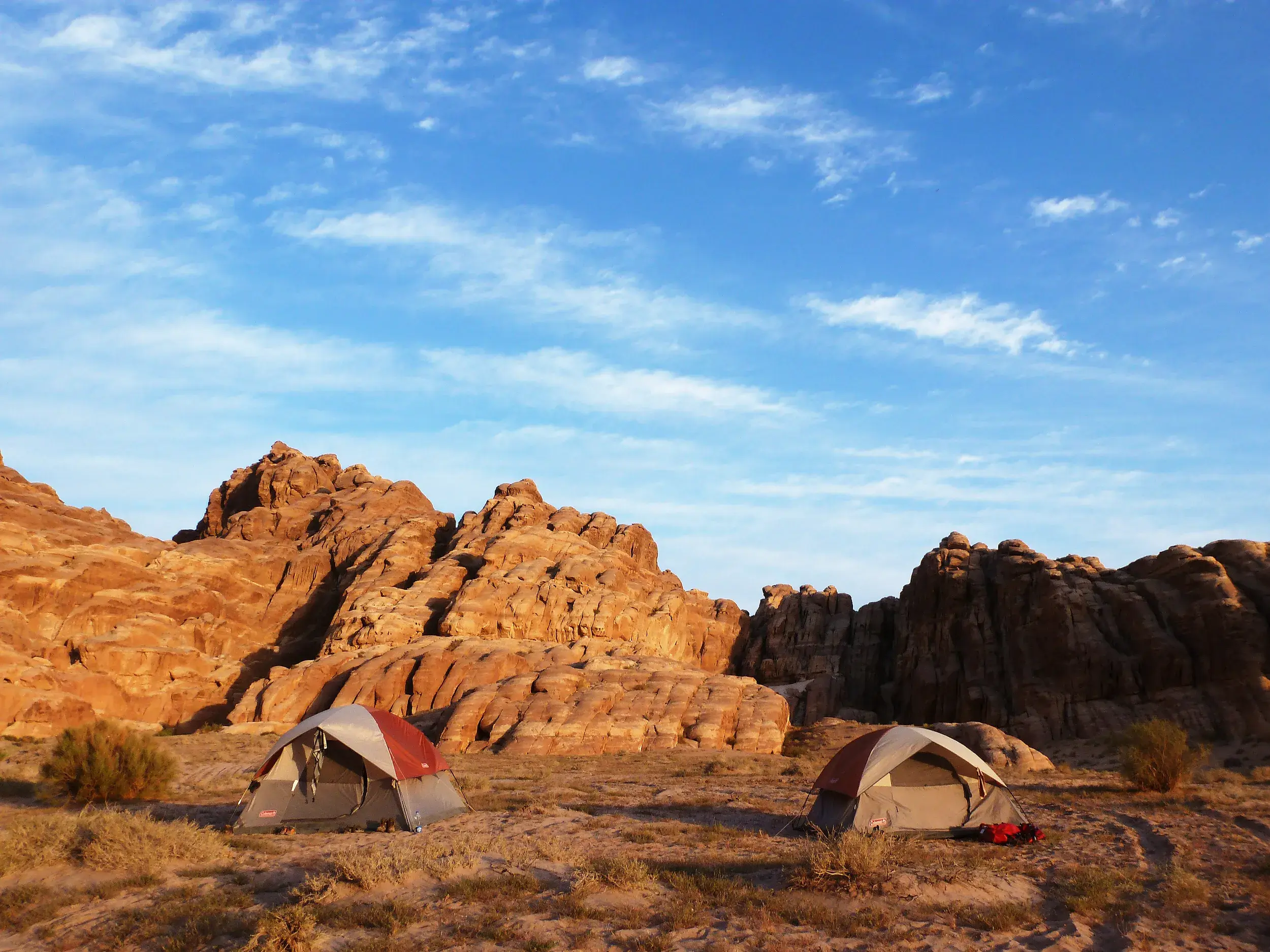 Zwei Zelte eines Trekking-Camps in der roten Felsenwüste des Wadi Rum in Jordanien unter blauem Himmel.