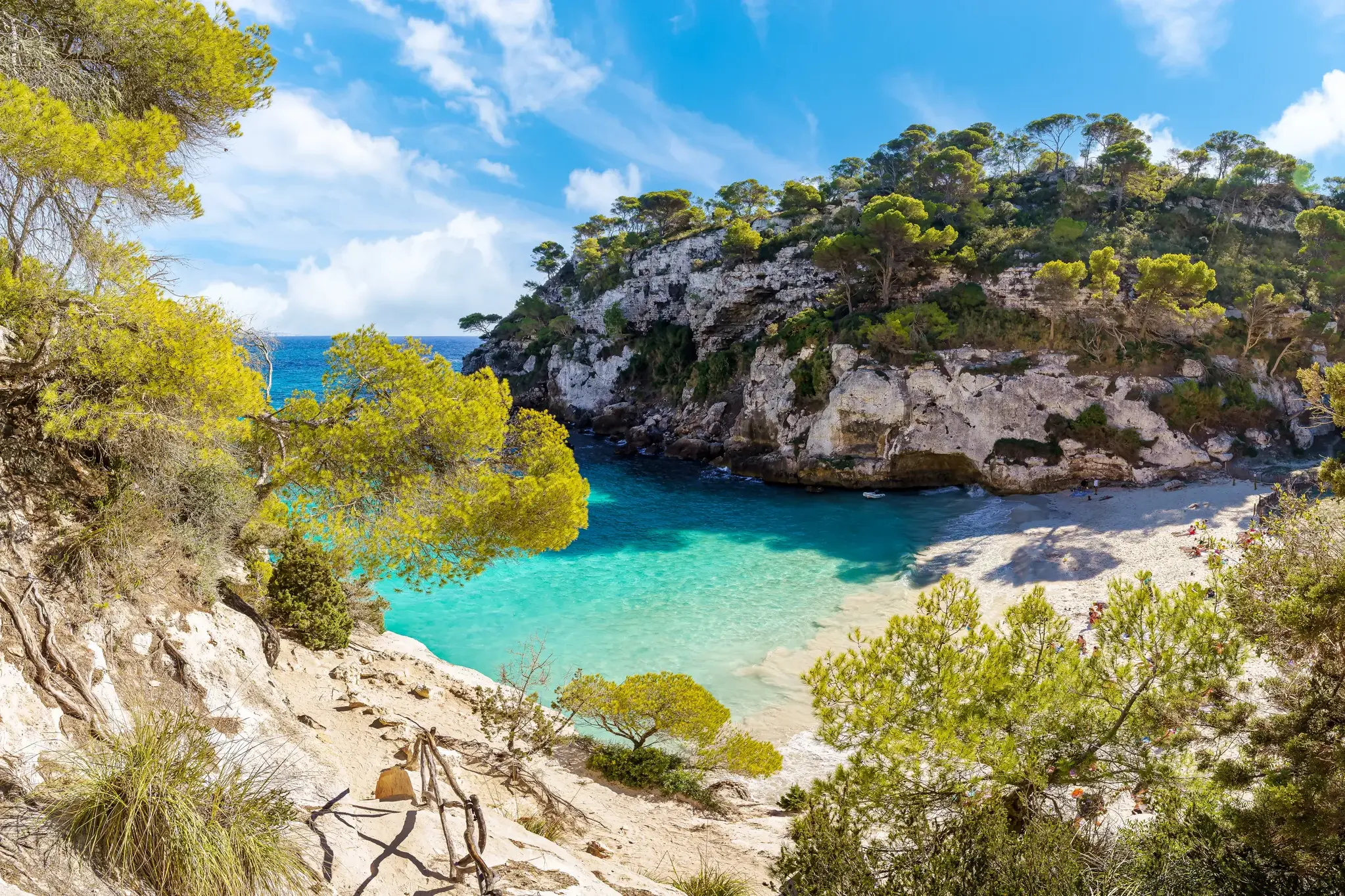 Blick von einem Wanderweg auf die Bucht Cala Macarella mit türkisfarbenem Wasser und Sandstrand auf Menorca.