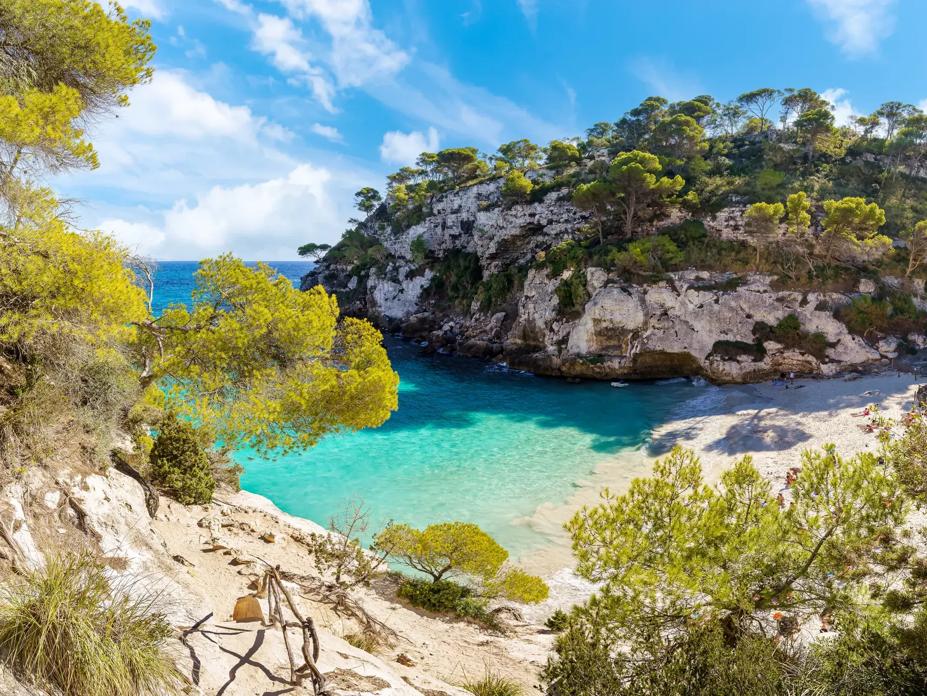 Blick von einem Küstenwanderweg auf die paradiesische Bucht Cala Macarella auf Menorca mit türkisblauem Wasser.