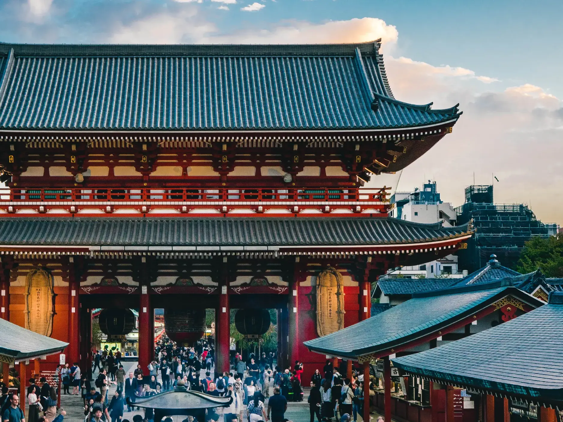 Menschenmenge vor dem rot-weißen Hōzōmon-Tor des Sensō-ji-Tempels im Tokyoter Stadtteil Asakusa bei Sonnenuntergang.