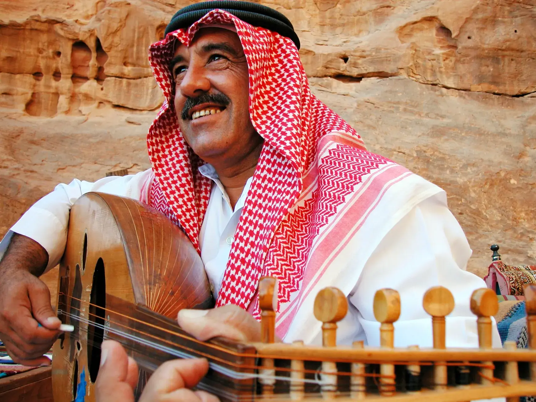 Einheimischer Beduine teilt seine Musik und spielt lächelnd auf der Oud in der Felslandschaft von Wadi Rum.