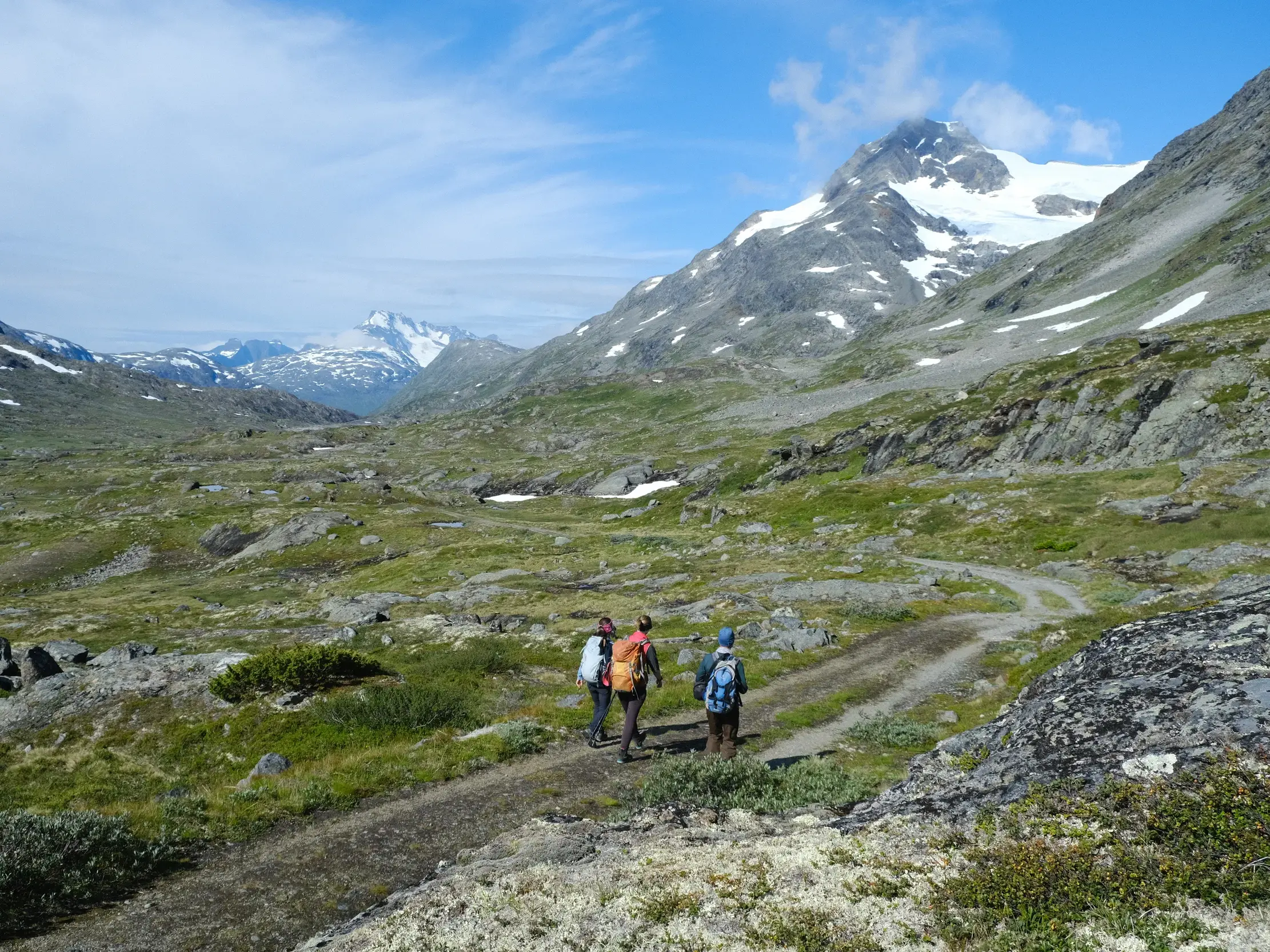Eine kleine Wandergruppe auf Trekking-Tour durch den Jotunheimen Nationalpark in Norwegen mit Blick auf Bergmassive.