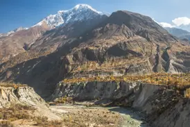 Majestätischer, schneebedeckter Rakaposhi-Gipfel über dem herbstlichen Hunzatal mit einem Flussbett in Nordpakistan.