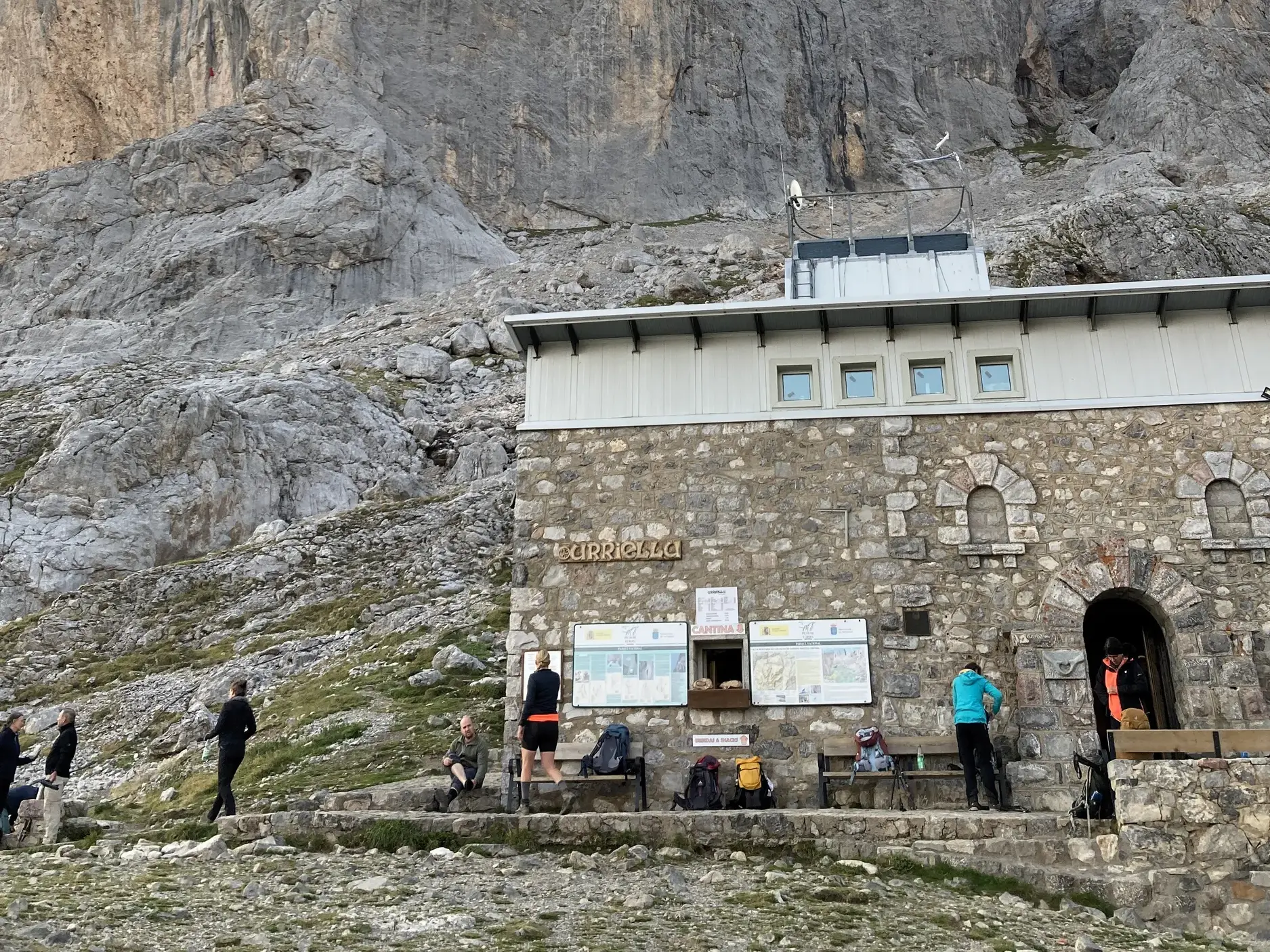 Eine Hauser-Trekkinggruppe rastet vor der Vega de Uriellu-Hütte am Fuße des markanten Naranjo de Bulnes in Asturien.