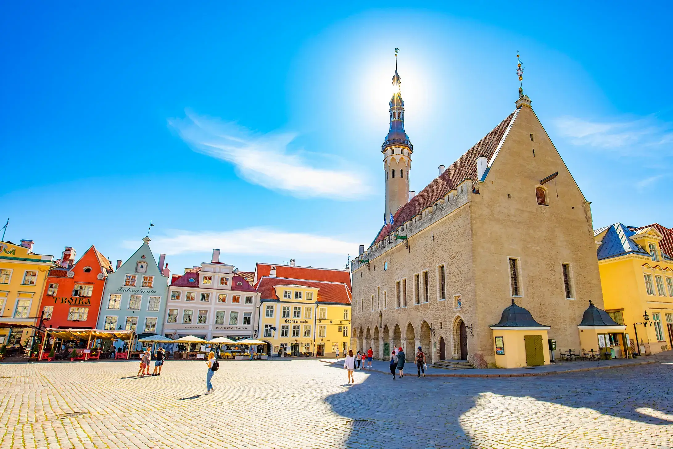 Sonnendurchfluteter Rathausplatz in Tallinn mit dem gotischen Rathaus und bunten, historischen Giebelhäusern.