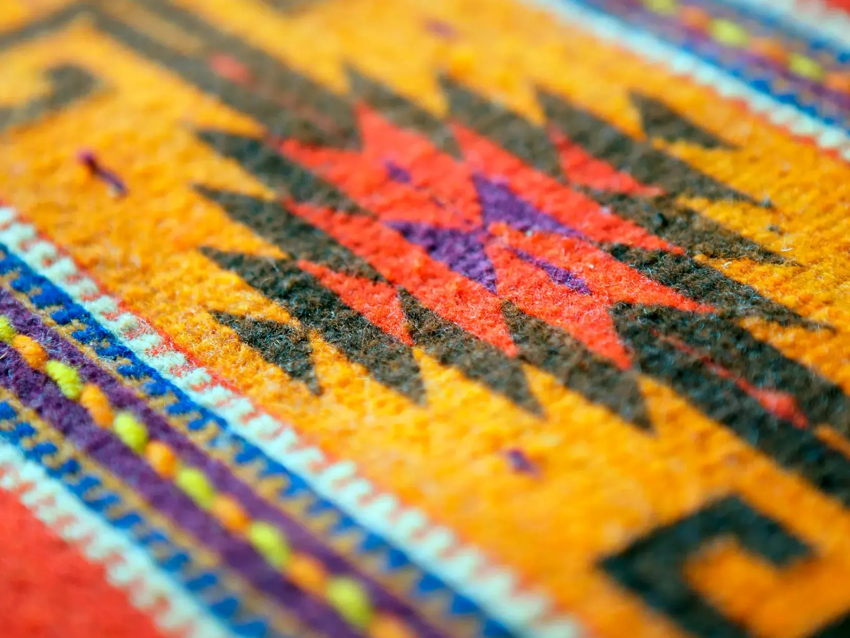 Nahaufnahme eines traditionellen mexikanischen Stoffes mit farbenfrohen, geometrischen Mustern der alten Maya-Webkunst.