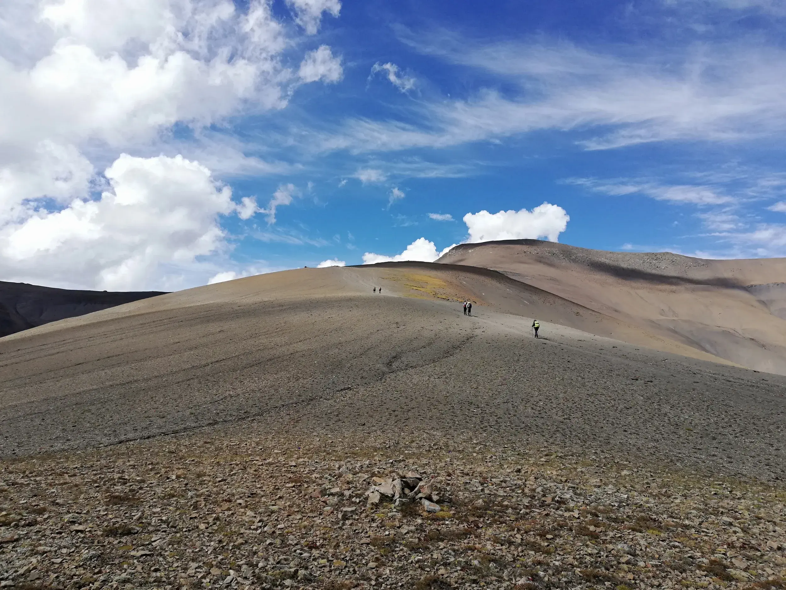 Weite, karge Berglandschaft im Dolpo, Nepal, mit einer kleinen Trekkinggruppe auf dem Weg über einen hohen Pass.