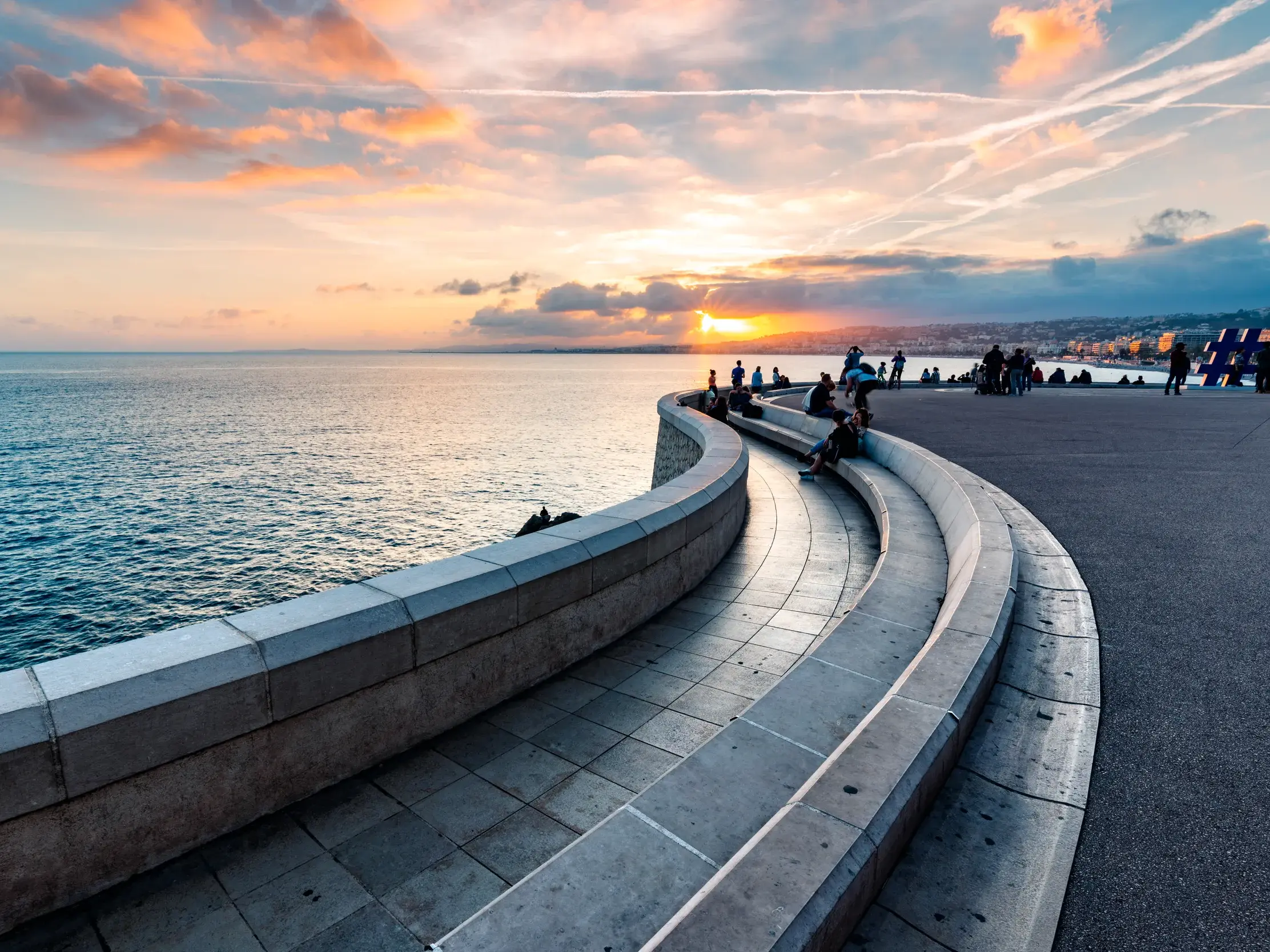 Malerischer Sonnenuntergang über der Engelsbucht in Nizza, gesehen von der geschwungenen Aussichtsterrasse am Ende der Promenade des Anglais.