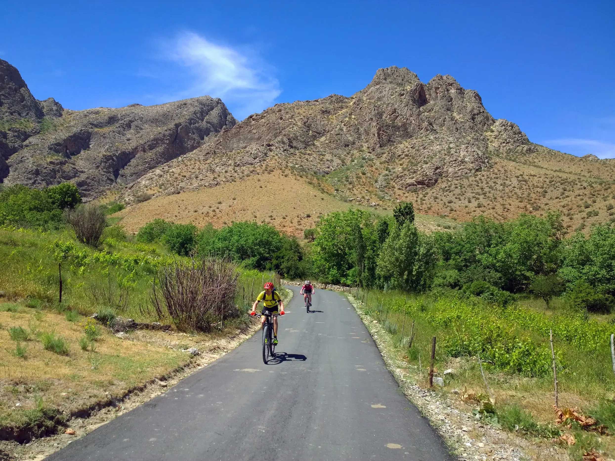 Zwei Radfahrer auf einer Hauser Radreise durch die hügelige Landschaft des Chatkal-Gebirges bei Parkent in Usbekistan.