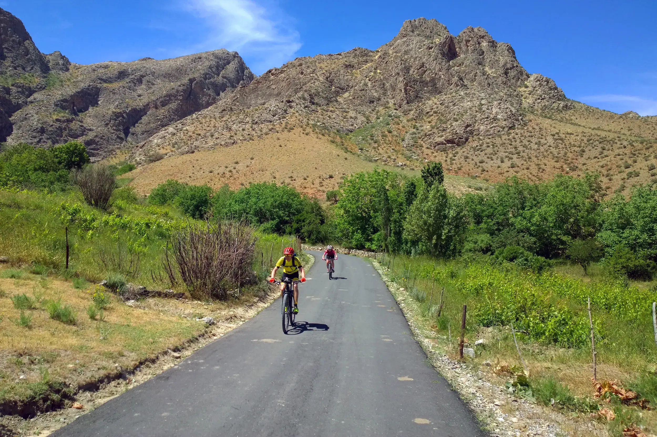 Zwei Radfahrer auf einer Hauser Radreise durch die hügelige Landschaft des Chatkal-Gebirges bei Parkent in Usbekistan.