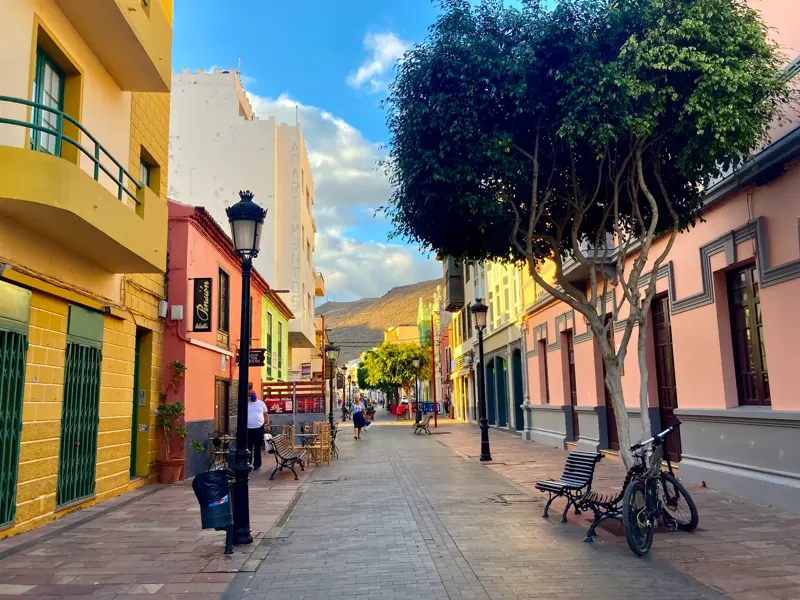 Sonnige Gasse mit bunten Kolonialhäusern und einem Baum in der Altstadt von Los Llanos de Aridane auf der Insel La Palma.