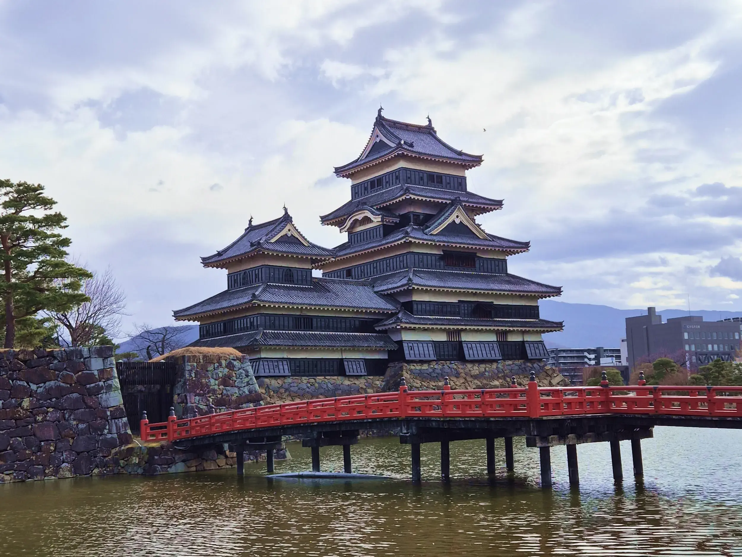 Die imposante Krähenburg Matsumoto in den Japanischen Alpen mit der roten Brücke, die über den Wassergraben führt.