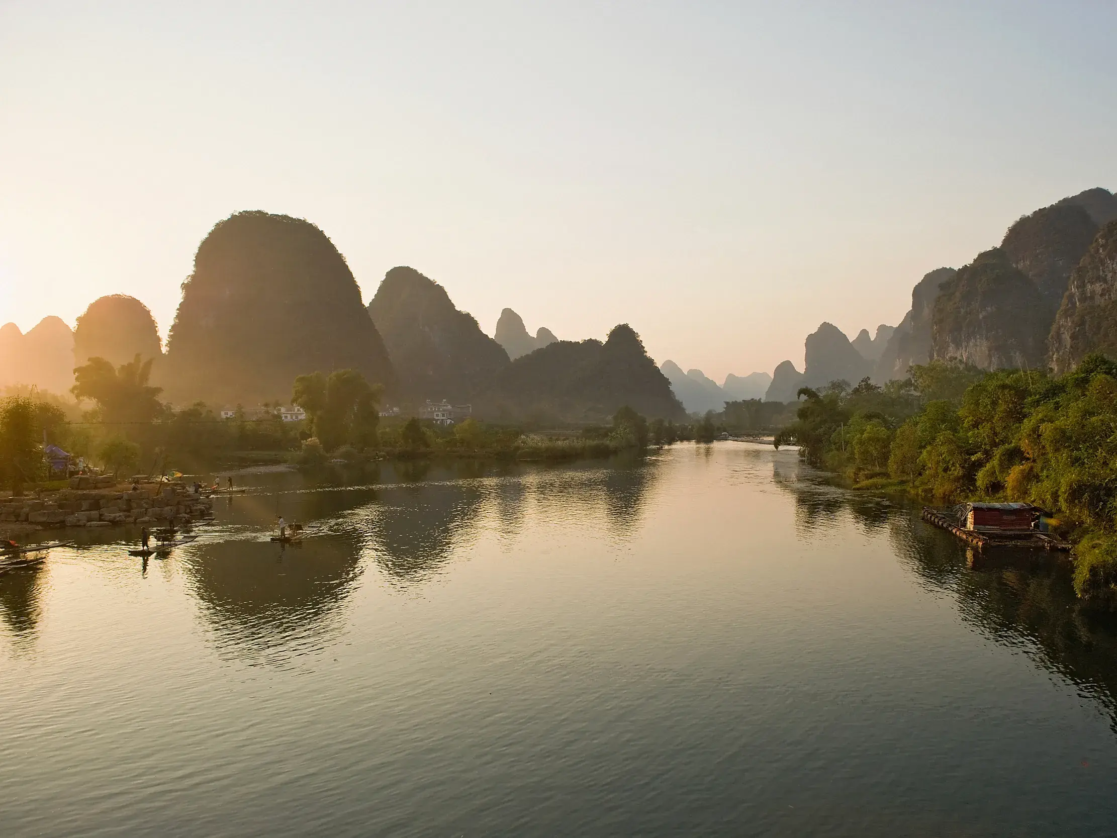 Fahrt mit dem Bambusfloß auf dem Li-Fluss durch die magische Landschaft der Kegelkarstberge bei Yangshuo im Morgenlicht.