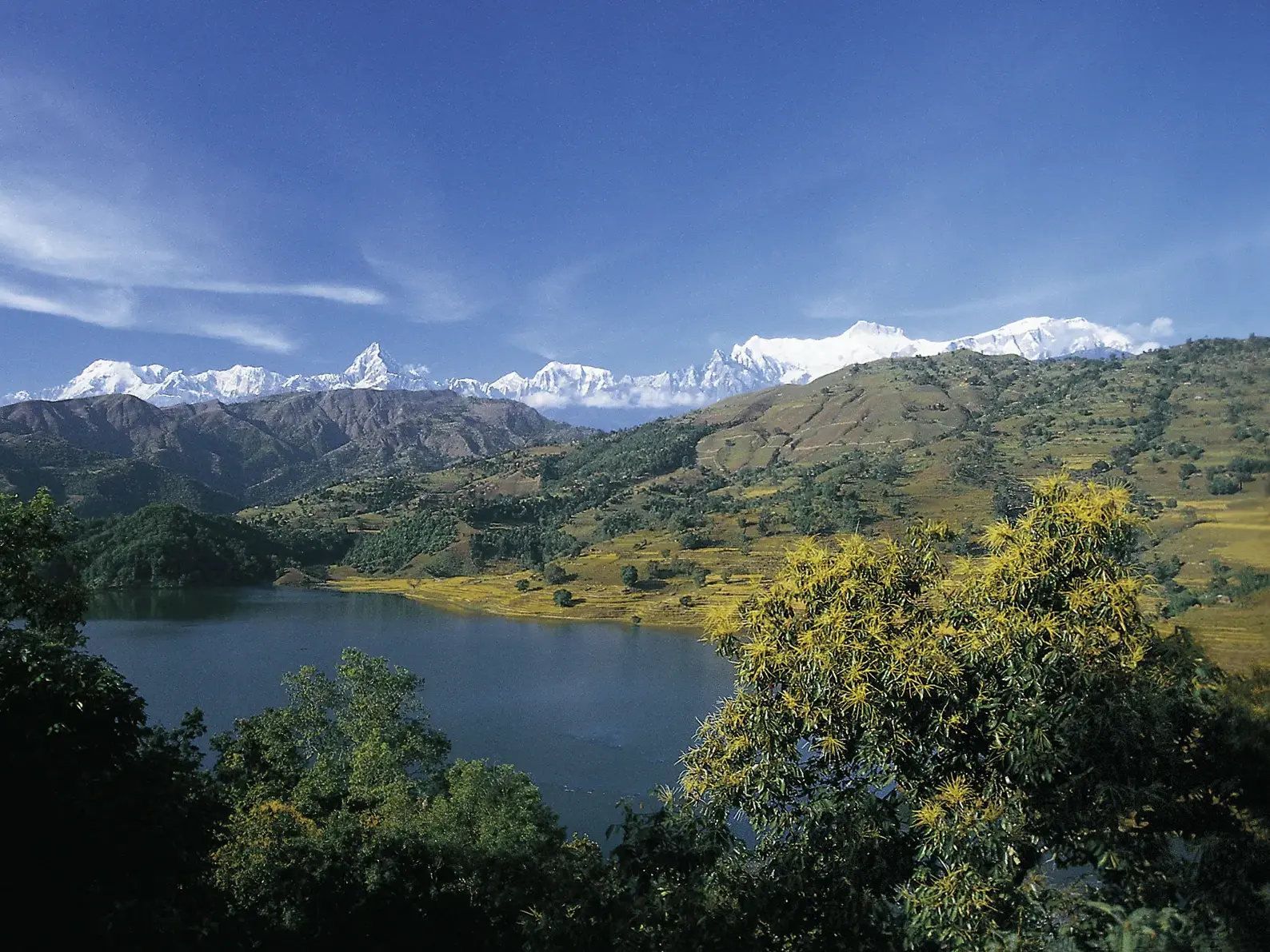 Panoramablick über den ruhigen Begnas See auf die majestätischen, schneebedeckten Gipfel des Annapurna im nepalesischen Himalaya.