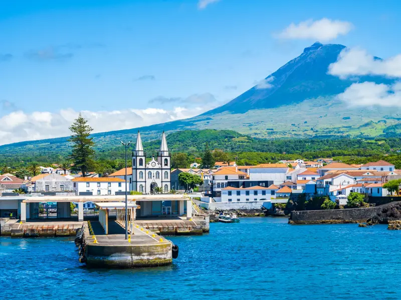 Hafeneinfahrt von Madalena auf der Azoren-Insel Pico mit der Kirche und dem majestätischen Vulkan Pico im Hintergrund.
