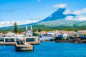 Hafeneinfahrt von Madalena auf der Azoren-Insel Pico mit der Kirche und dem majestätischen Vulkan Pico im Hintergrund.