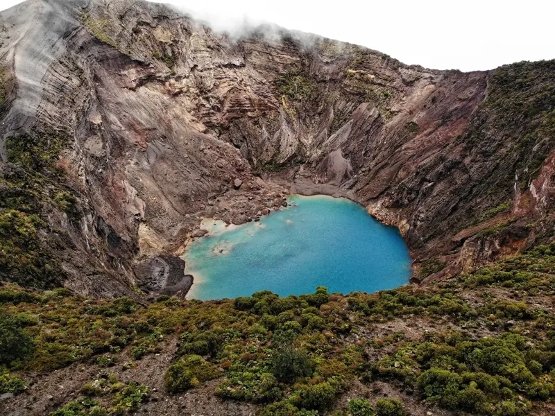 Blick in den kargen Vulkankrater Irazú mit seinem leuchtend türkisen Kratersee während einer Wanderreise in Costa Rica.