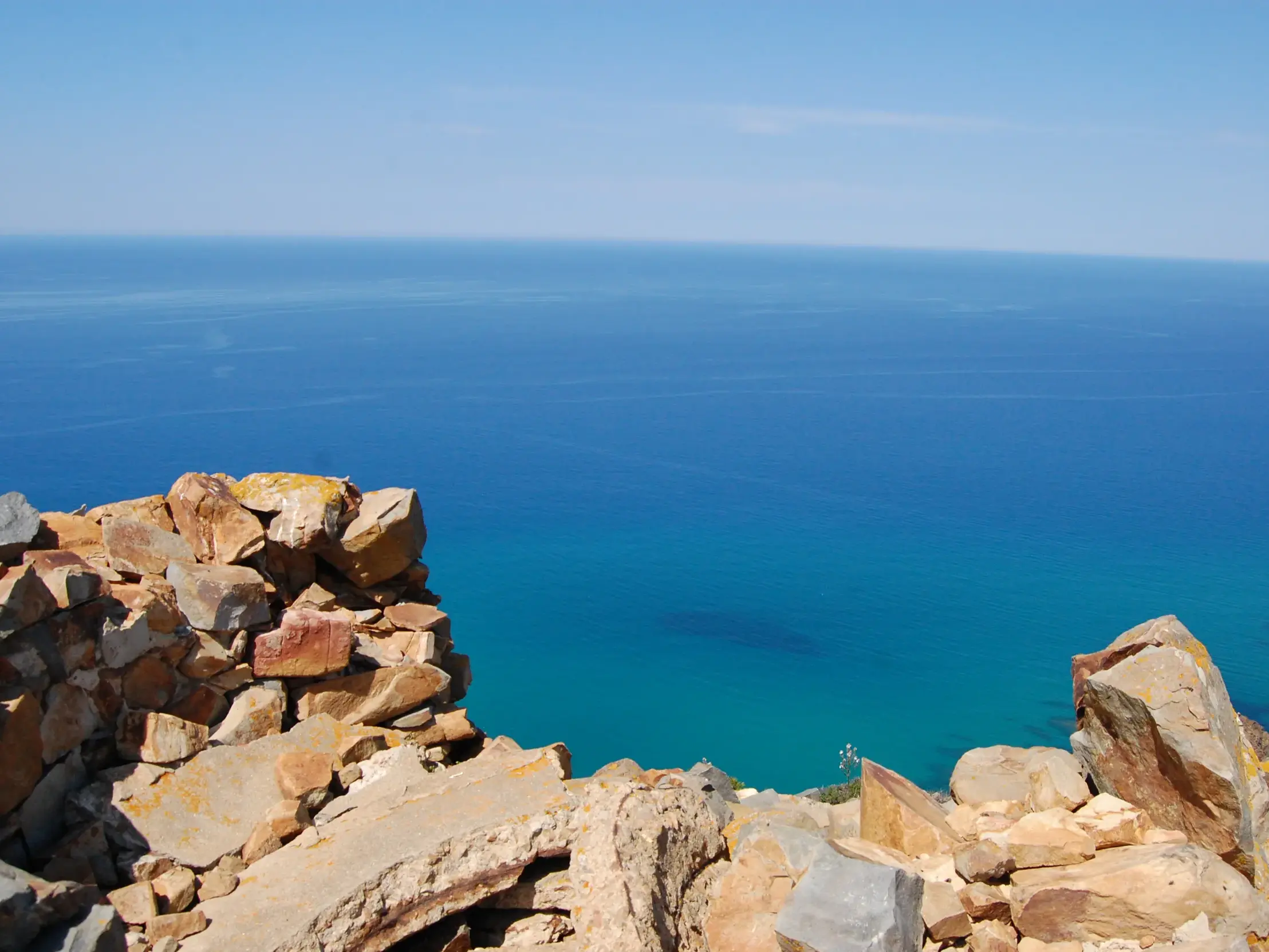 Ausblick von der Ruine eines Wachturms auf einer Küstenwanderung auf Sardinien über das tiefblaue Mittelmeer.