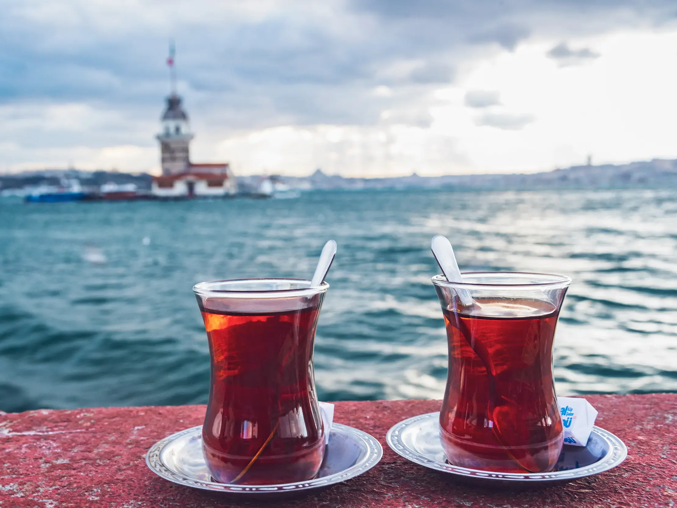 Zwei Gläser türkischer Schwarztee auf einer Mauer mit Blick auf den Mädchenturm, der im Bosporus in Istanbul steht.