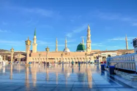 Die Prophetenmoschee in Medina mit grüner Kuppel und Minaretten spiegelt sich im polierten Boden des weitläufigen Vorplatzes.