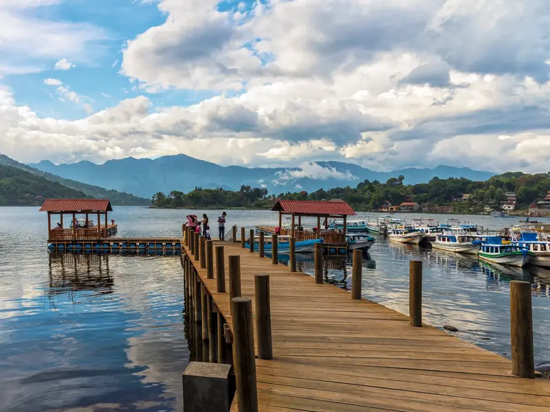 Eine Kleingruppe auf einem Holzsteg am Lago de Atitlán in Guatemala, umgeben von Booten und der malerischen Kulisse der Vulkane.