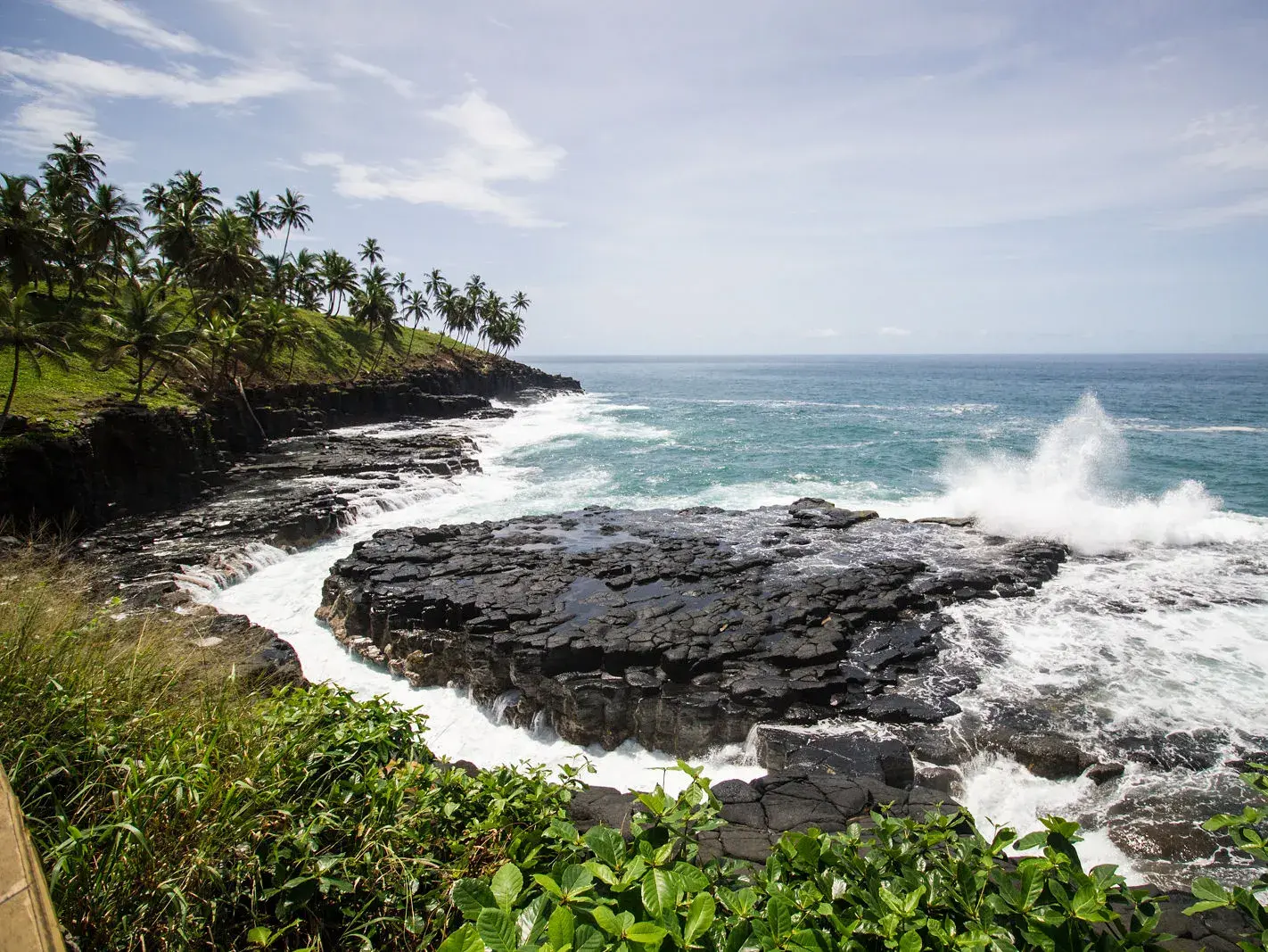 Tosende Wellen des Atlantiks brechen an der wilden, palmengesäumten Vulkanküste von São Tomé nahe des Boca do Inferno.