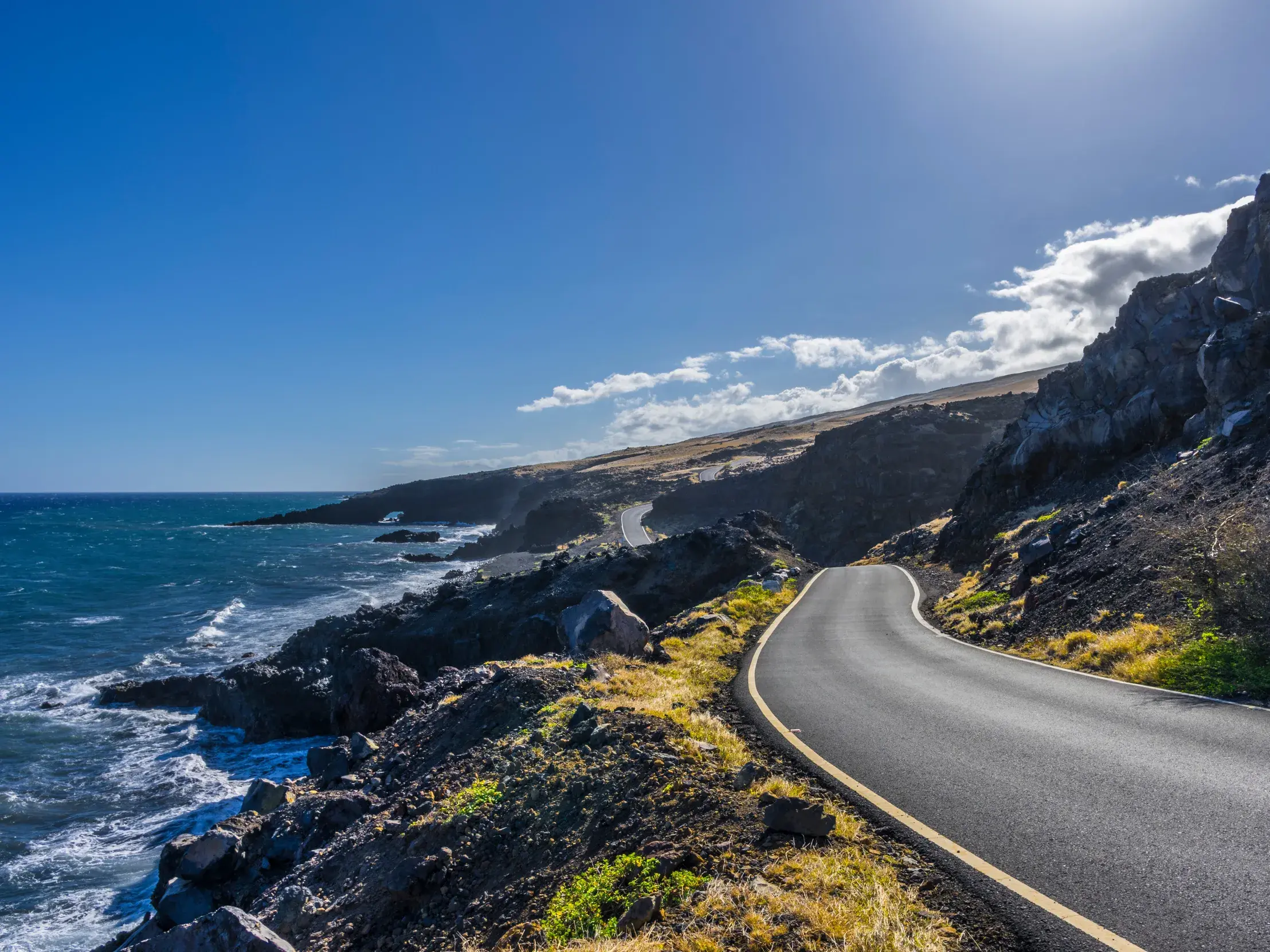 Sonnige Fahrt auf der kurvenreichen Küstenstraße nach Hana auf Maui, vorbei an schroffer Vulkanküste und dem Pazifik.