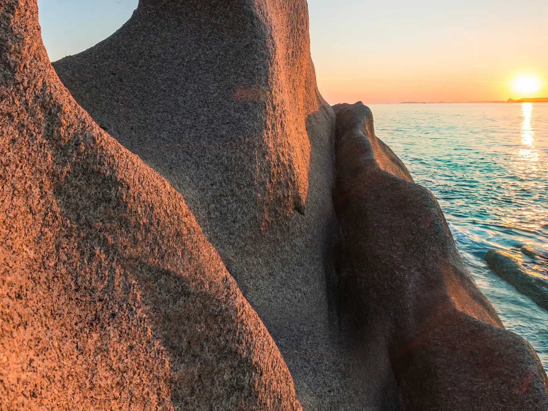 Bizarre, windgeschliffene Granitfelsen am Capo Testa auf Sardinien im warmen Licht des Sonnenuntergangs am Meer.