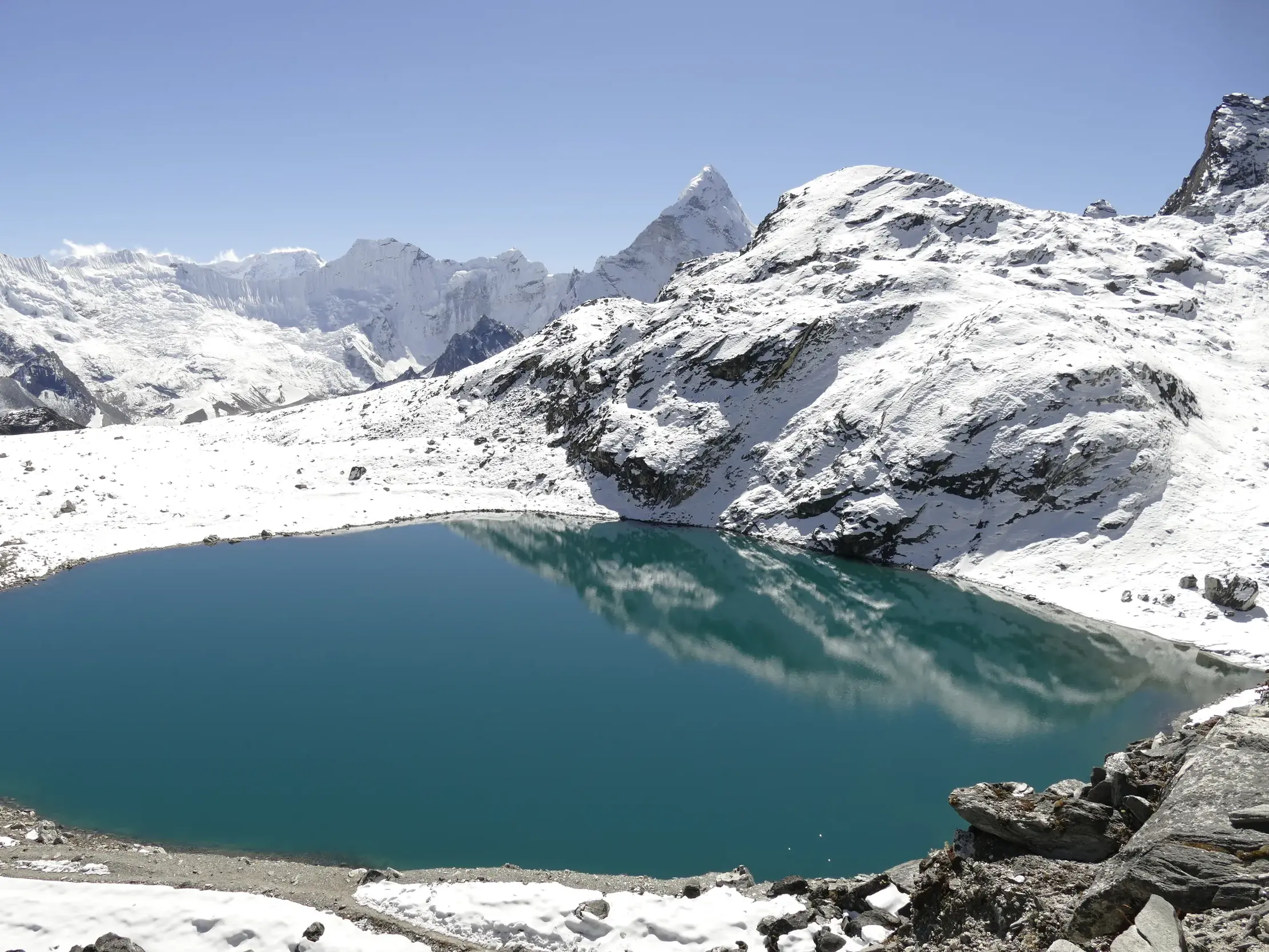 Blick vom Renjo La Pass auf den türkisfarbenen Gokyo-See und die schneebedeckten Gipfel des Himalaya in Nepal.