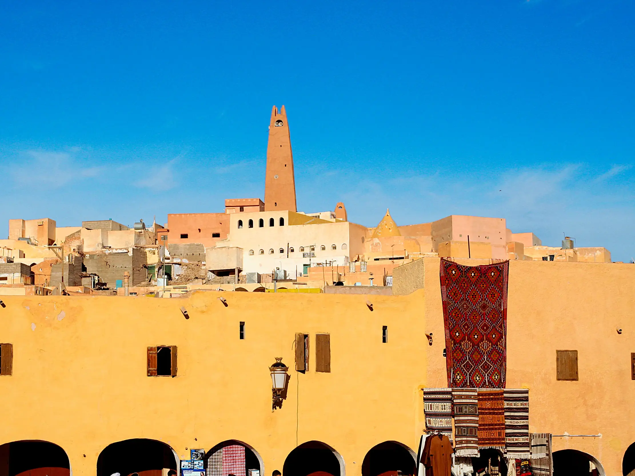 Die einzigartige Wüstenarchitektur der Oasenstadt Ghardaia (UNESCO-Welterbe) mit Minarett und buntem Markttreiben.