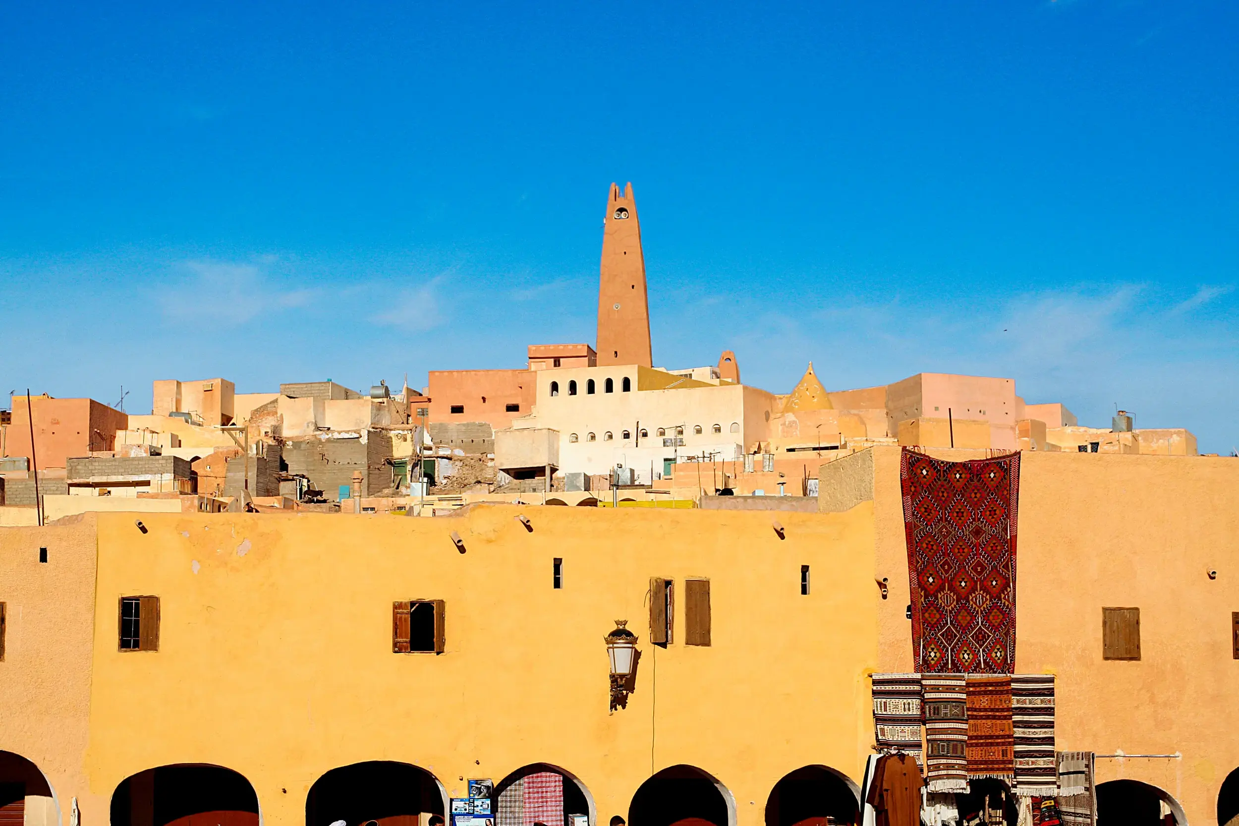 Die einzigartige Wüstenarchitektur der Oasenstadt Ghardaia (UNESCO-Welterbe) mit Minarett und buntem Markttreiben.