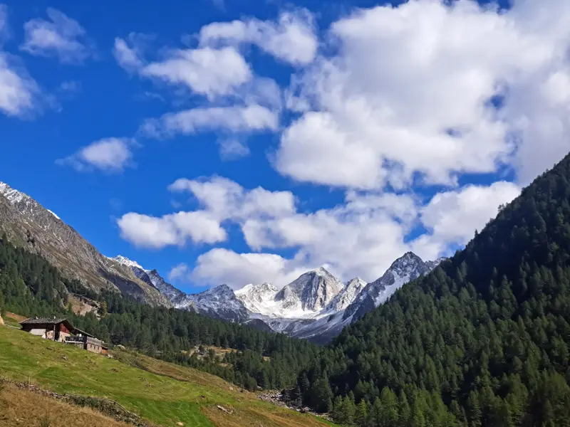 Eine Berghütte im Pfossental während einer Trekkingtour in Südtirol mit Blick auf die schneebedeckten Ötztaler Alpen.