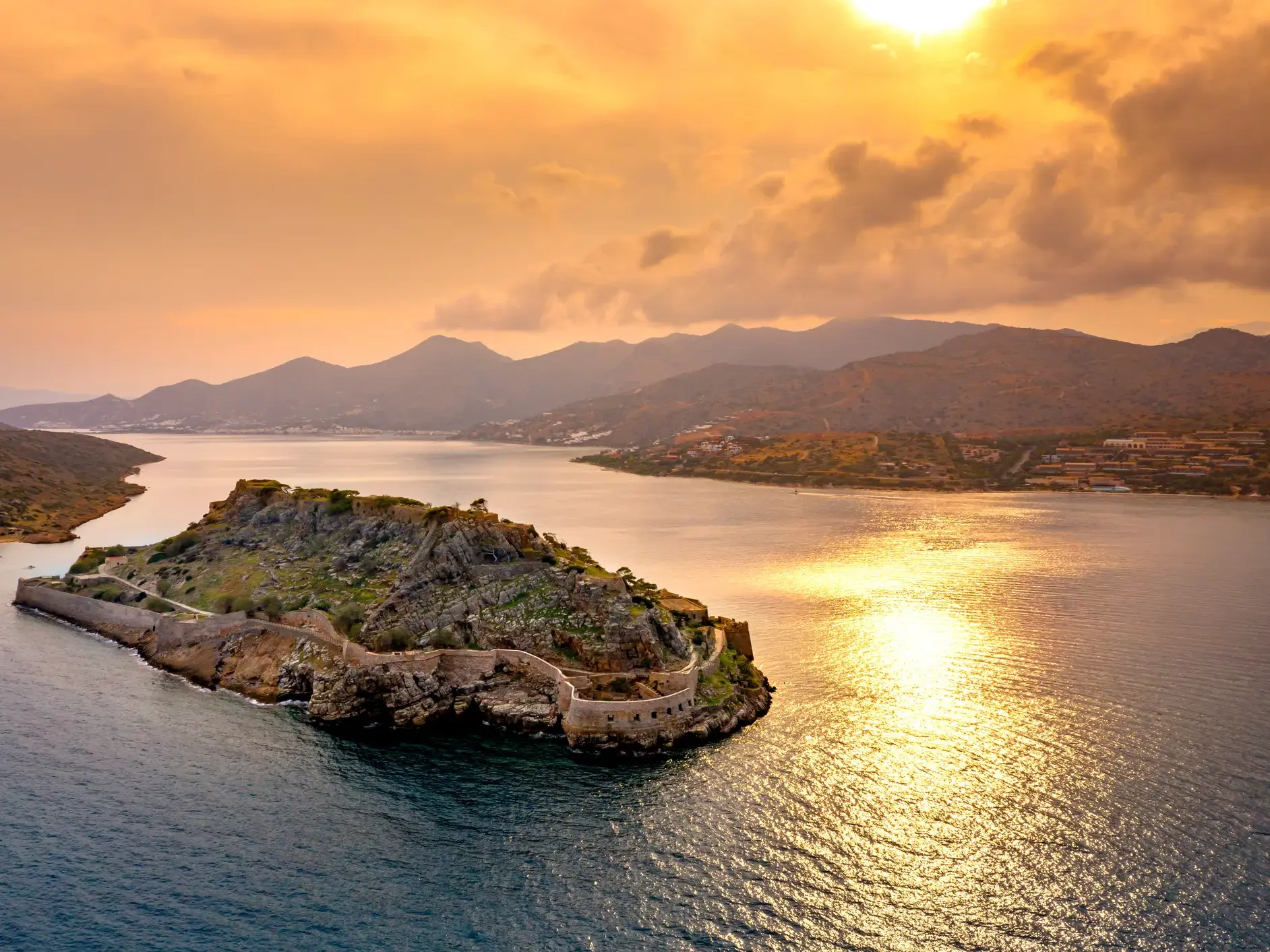 Die historische Festungsinsel Spinalonga auf Kreta, stimmungsvoll beleuchtet vom Sonnenuntergang über der Bucht von Mirabello.