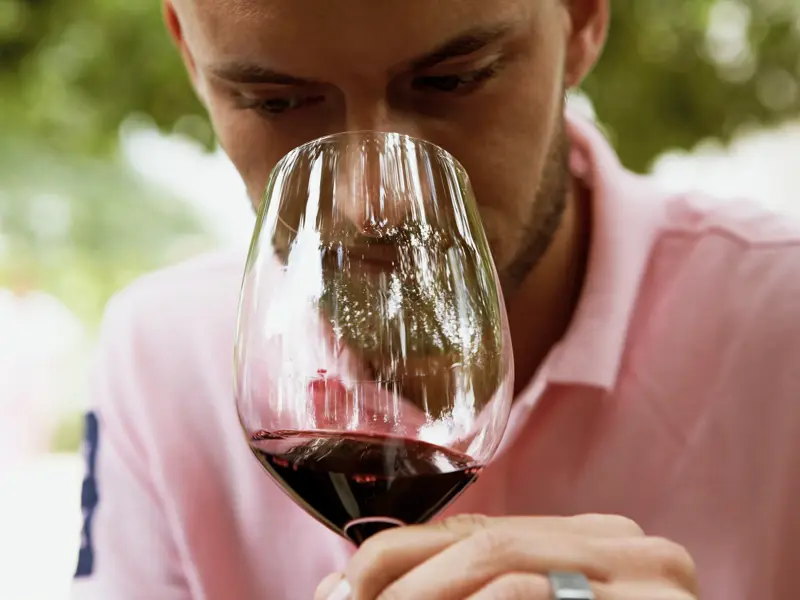 Ein Reiseteilnehmer prüft konzentriert das Bouquet eines Rotweins bei einer Weinprobe in St-Emilion bei Bordeaux.