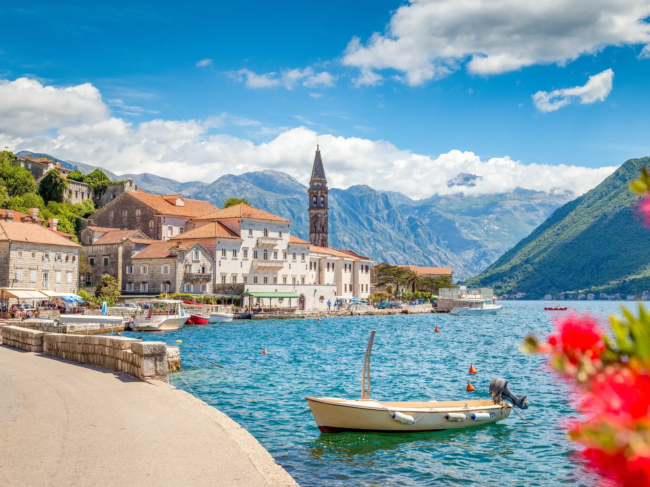 Malerische Küstenansicht der Bucht von Kotor in Montenegro mit Kirchturm und hohen Bergen.