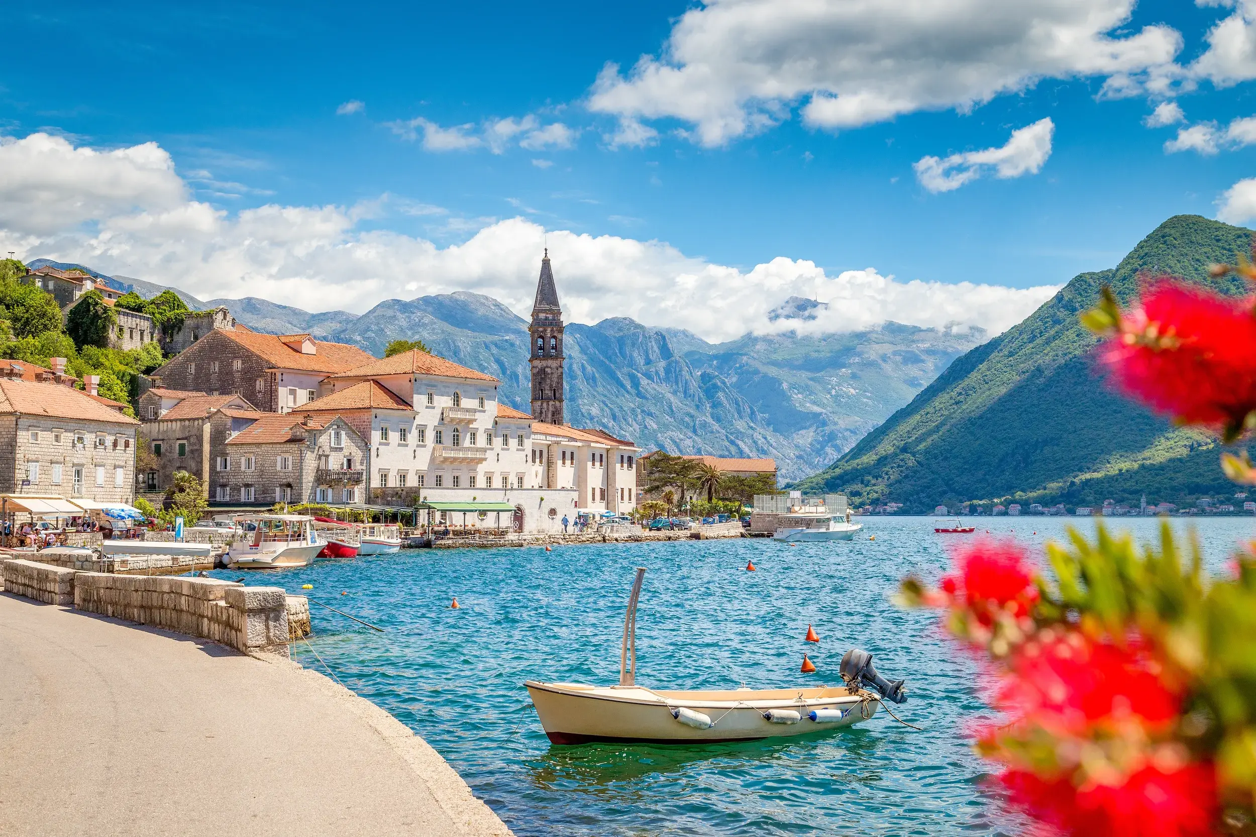 Malerische Küstenansicht der Bucht von Kotor in Montenegro mit Kirchturm und hohen Bergen.