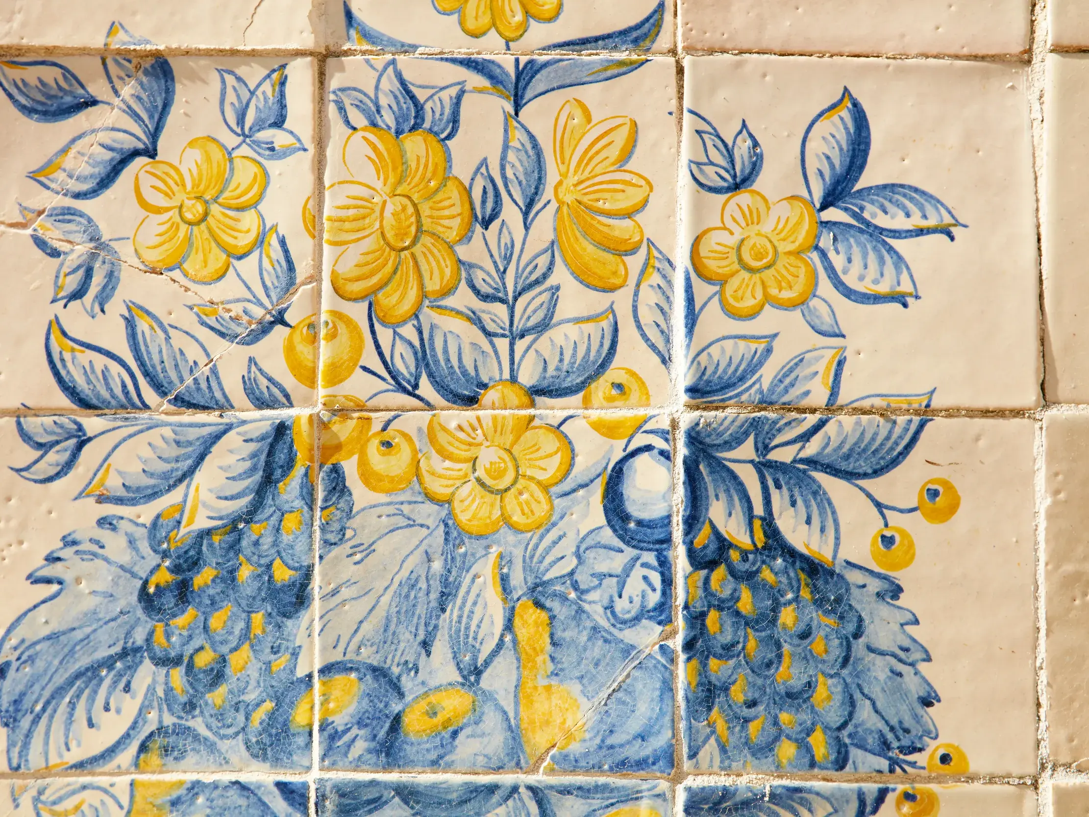 Traditionelle, handbemalte Azulejo-Kacheln mit blau-gelben Blumen, typisch für die Architektur in Städten wie Lissabon oder Porto.