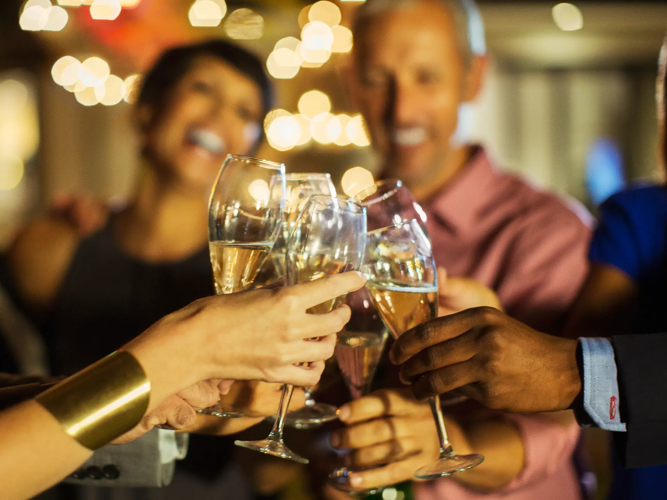 Fröhliche Gruppe von Singles und Alleinreisenden stößt in einem Restaurant in Warschau zu Silvester mit Sekt an.