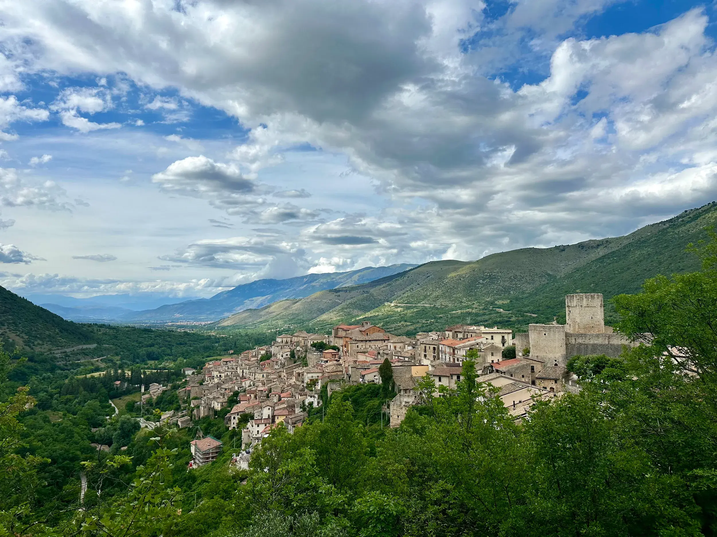 Das historische Bergdorf Scanno, eingebettet in die grüne Berglandschaft des Nationalparks Abruzzen unter bewölktem Himmel.