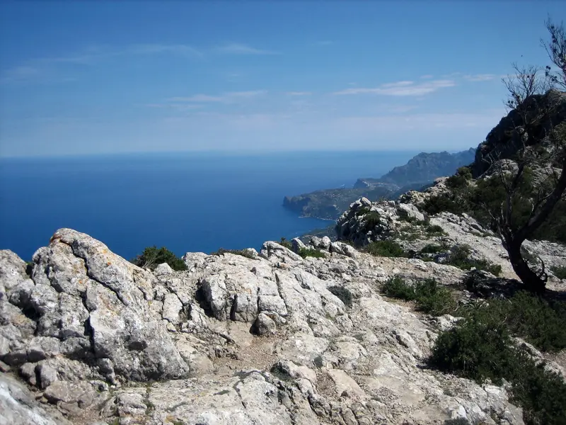 Felsiger Wanderweg in der Serra de Tramuntana mit Blick auf die Steilküste und das Meer auf Mallorca.