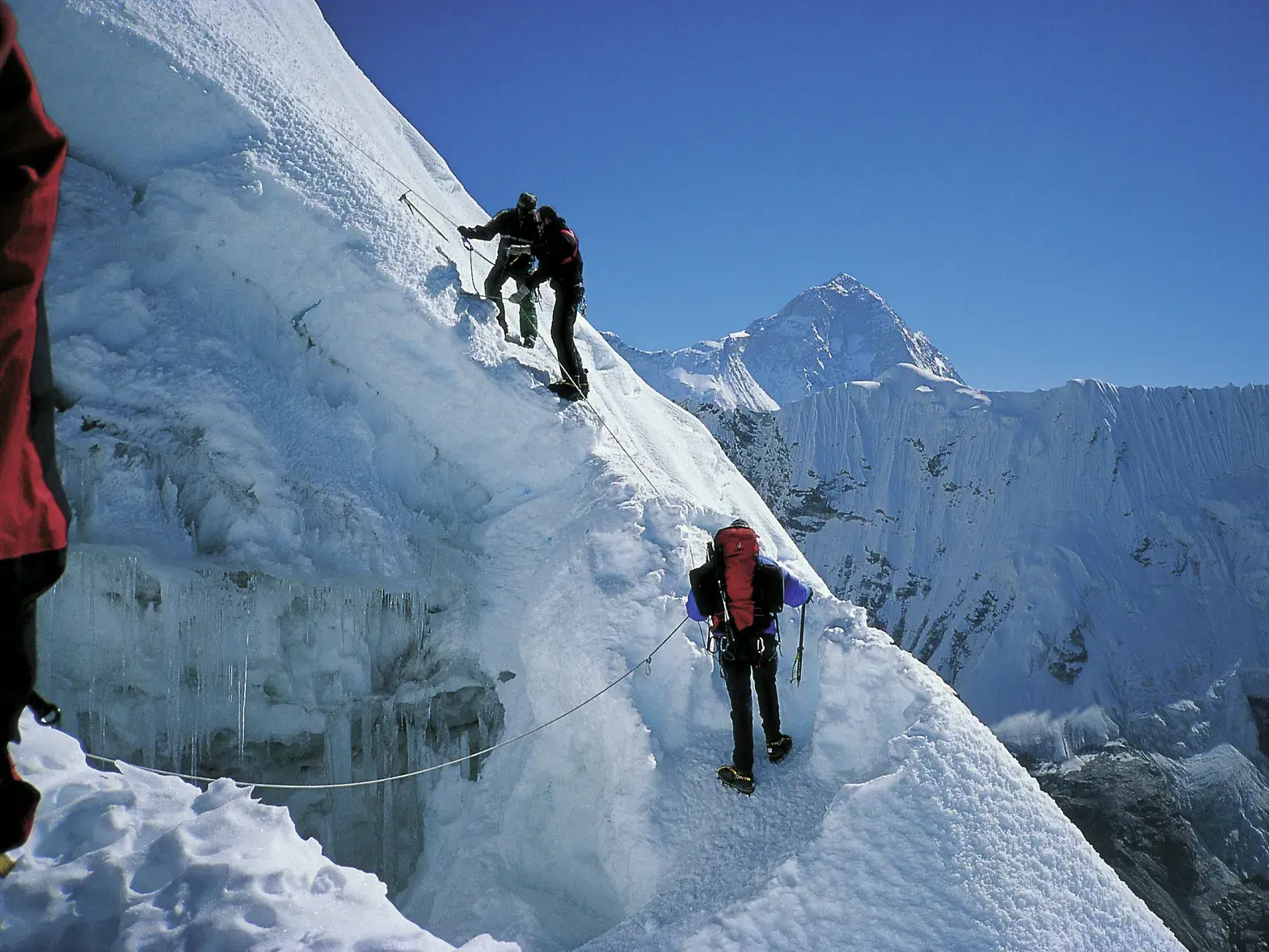 Drei Alpinisten bei der Gipfelbesteigung des Island Peak in Nepal, gesichert am Seil auf einer steilen Eisflanke.