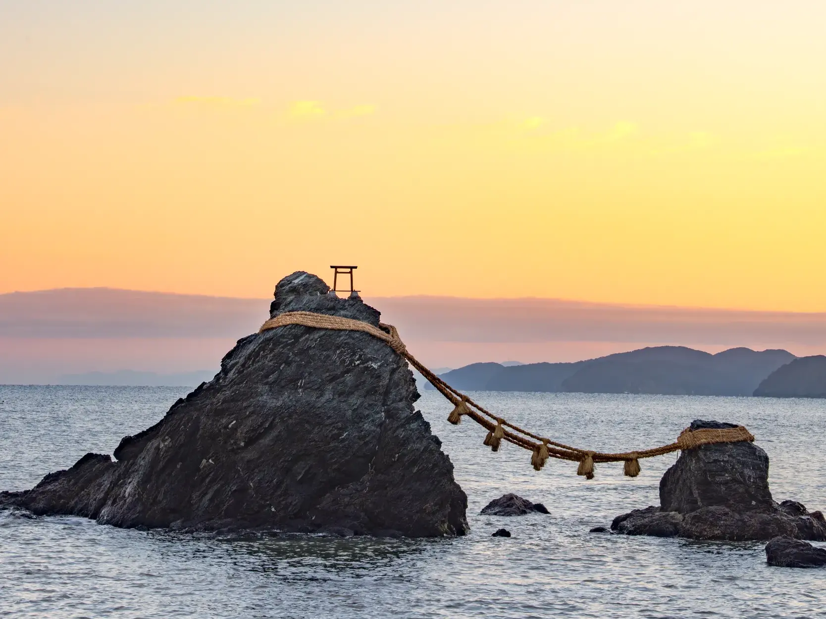 Die heiligen Ehefelsen Meoto-Iwa ragen bei Ise aus dem Meer, verbunden durch ein dickes Shimenawa-Seil bei Sonnenuntergang.