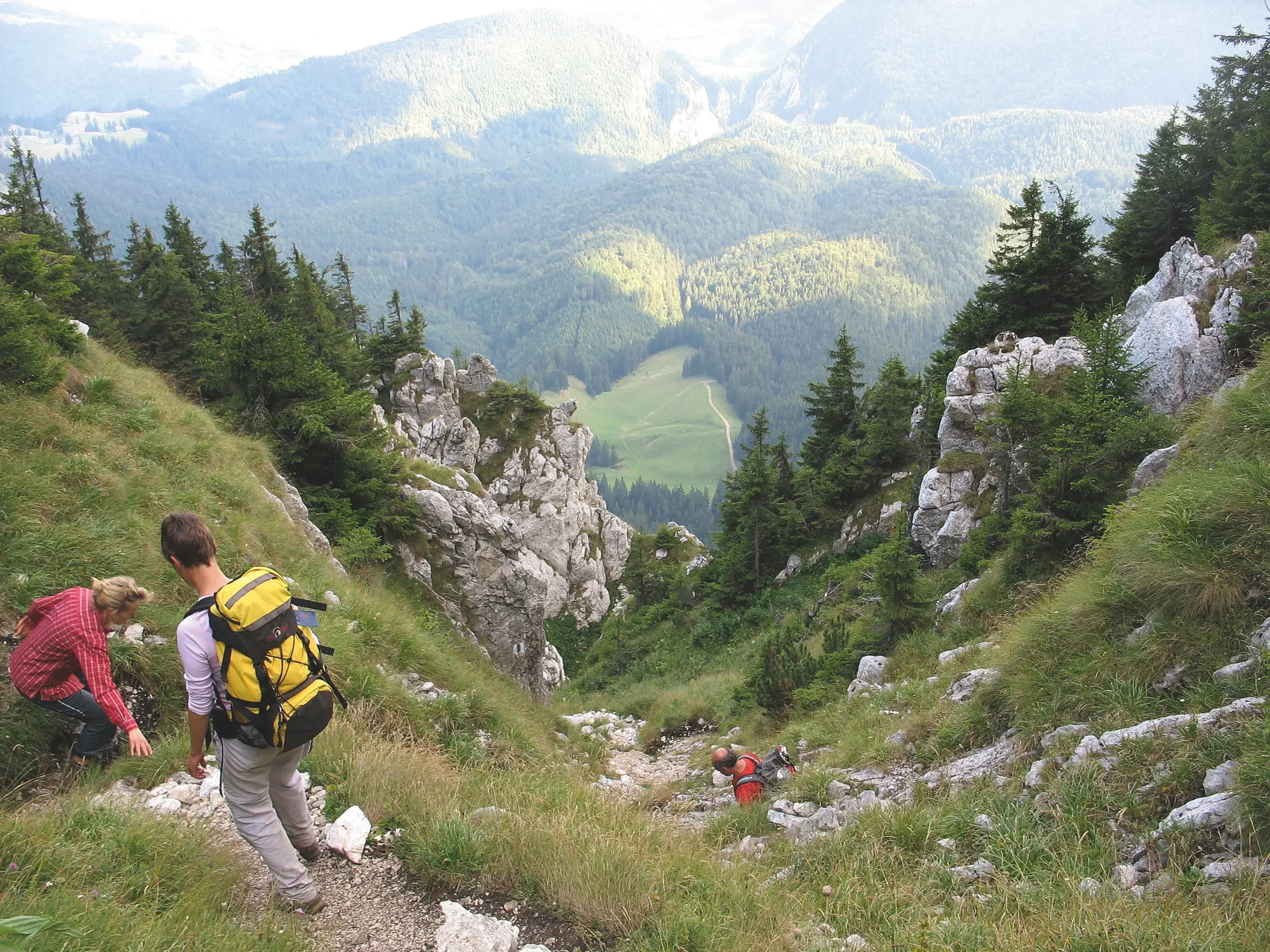 Eine Trekking-Gruppe beim Abstieg auf einem steilen Pfad im Fagaras Gebirge mit Blick auf die grünen Täler der Karpaten.