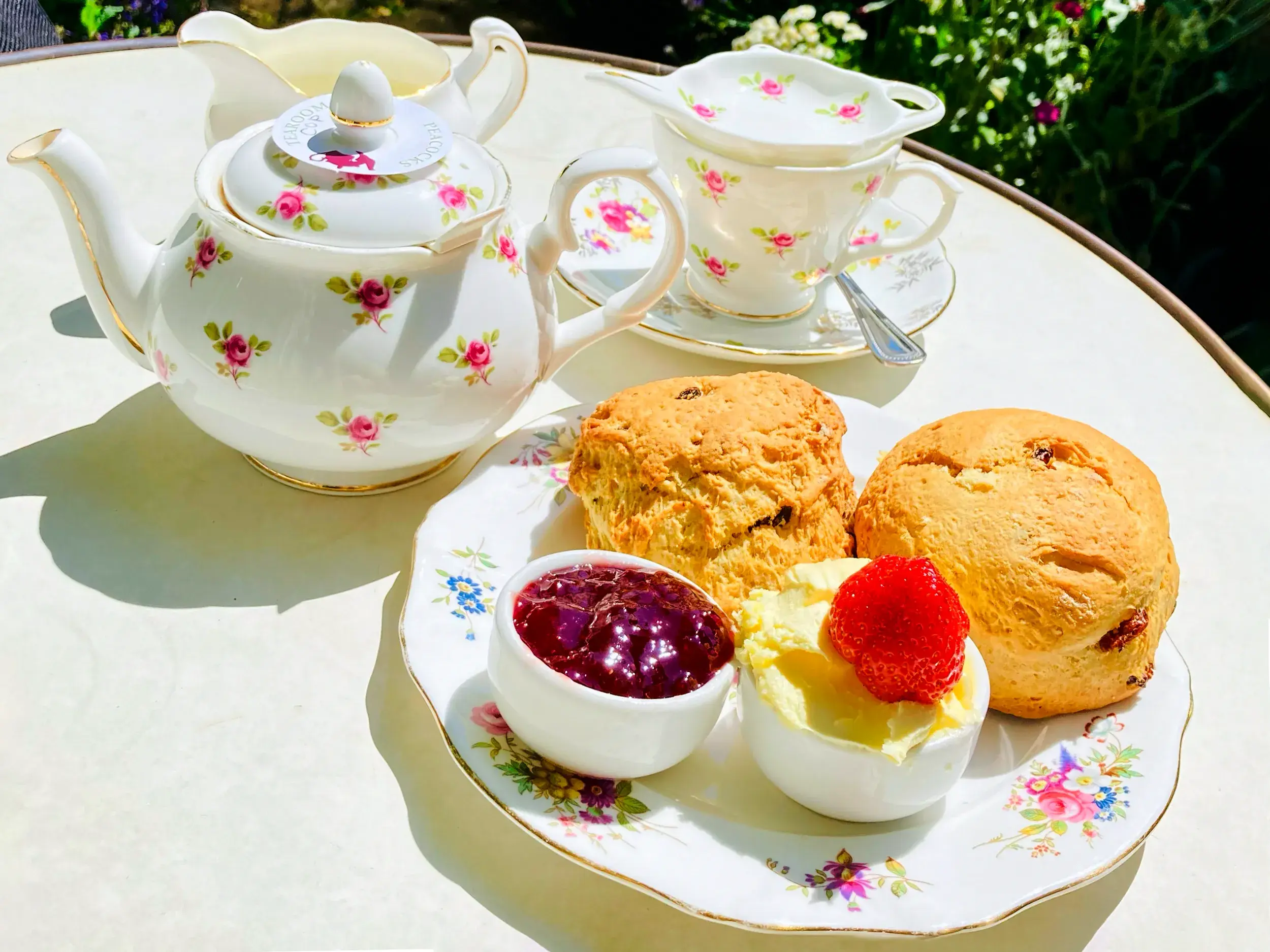 Klassischer englischer Cream Tea mit Scones, Clotted Cream und Marmelade, angerichtet auf floralem Porzellan in Südengland.