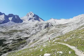 Eine Wandergruppe auf einem schmalen Bergpfad während einer Alpenüberquerung durch die hochalpine Felslandschaft Tirols.
