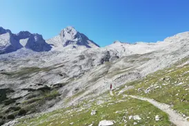 Eine Wandergruppe auf einem schmalen Bergpfad während einer Alpenüberquerung durch die hochalpine Felslandschaft Tirols.