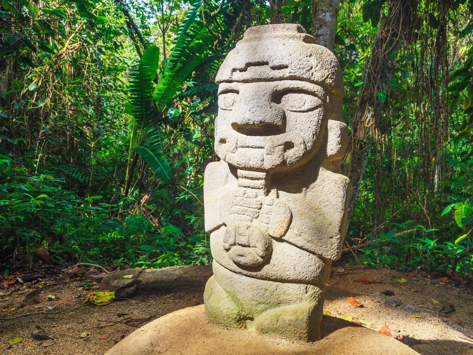 Mystische, präkolumbische Steinstatue umgeben von dichtem Dschungel im archäologischen Park von San Augustín in Kolumbien.