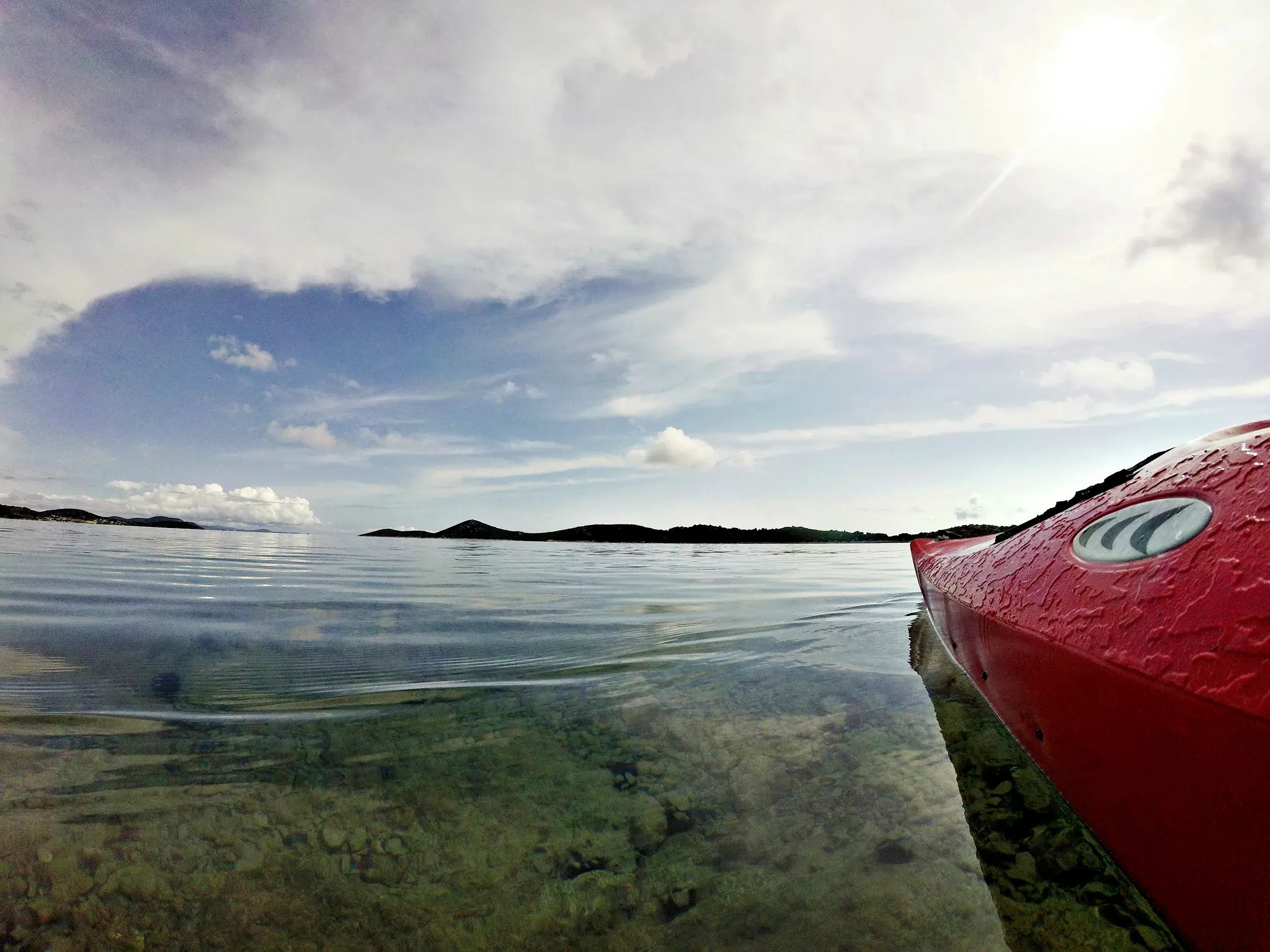 Aktiver Naturgenuss: Die Spitze eines roten Kajaks gleitet durch das kristallklare Wasser der kroatischen Adria.