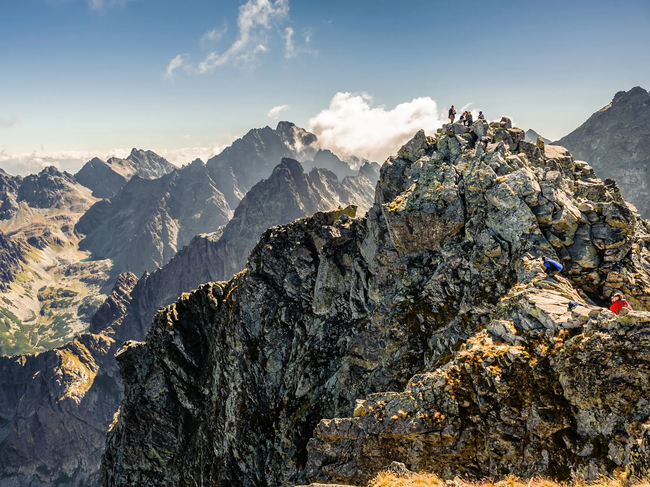 Eine Wandergruppe erklimmt den felsigen Gipfel des Rysy und genießt den weiten Panoramablick über die Hohe Tatra.